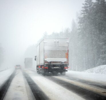Semi truck driving on a cold winter highway in Texas with light ice on the road representing winter fleet preparation and insurance readiness.