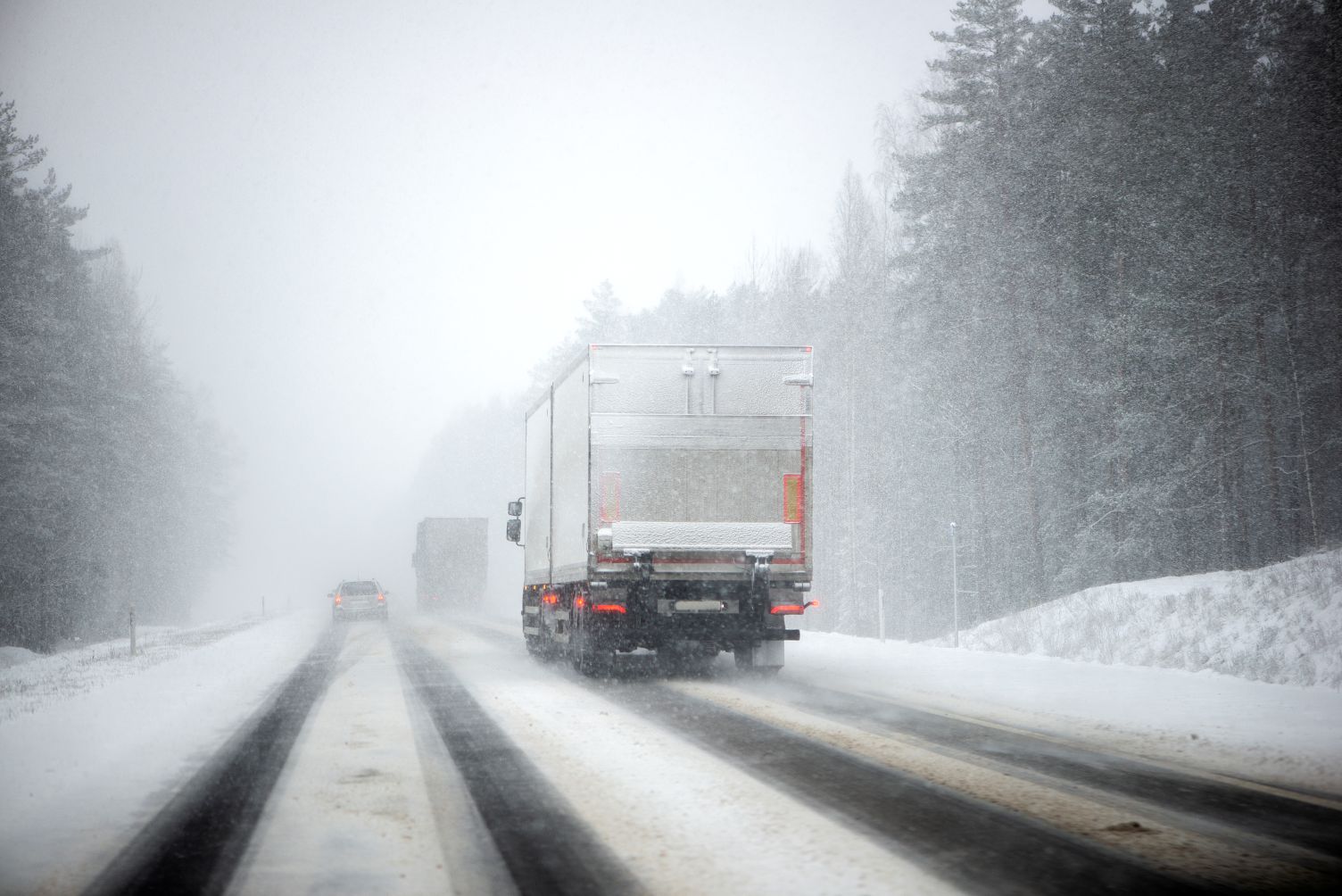 Semi truck driving on a cold winter highway in Texas with light ice on the road representing winter fleet preparation and insurance readiness.