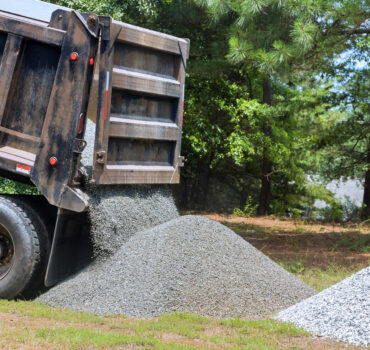 Dump truck hauling sand at construction site in Texas highlighting risks that impact sand and gravel trucking insurance